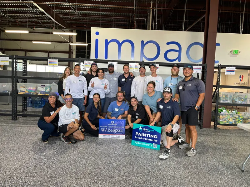 The Kind Home Painting team behind a Fill A Backpack donation banner at A Precious Child